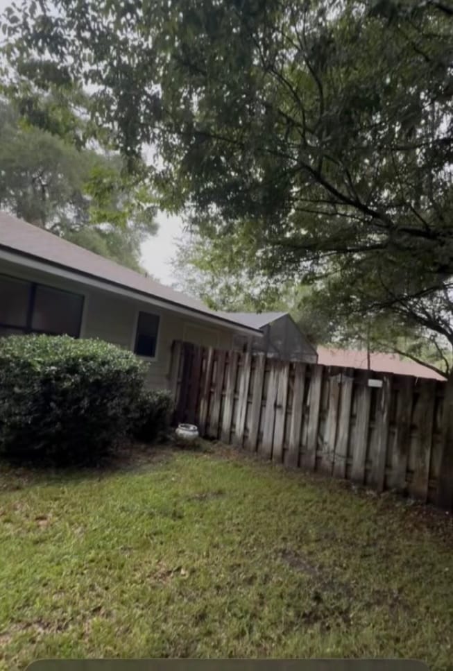 After — the same fence line with the limbs raised, the shrub shaped back and the grass cut.